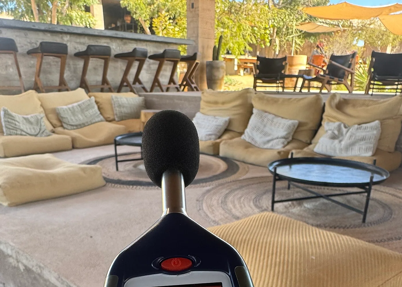 Medición de nivel sonoro en una terraza de hotel rodeada de vegetación.