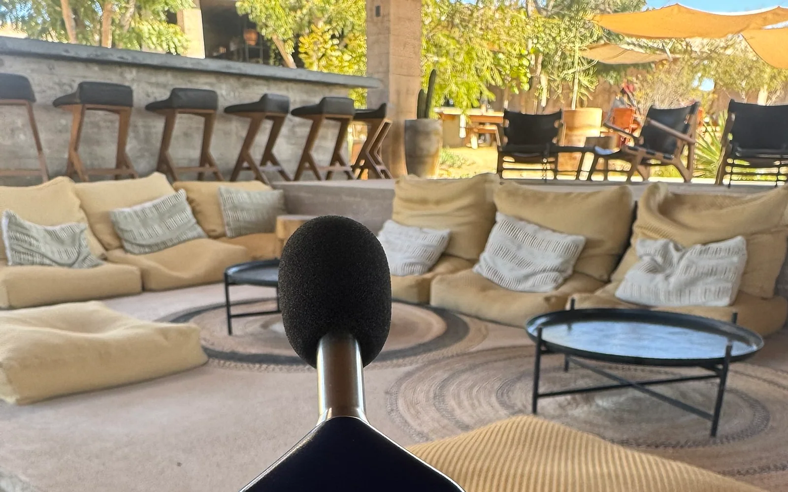 Medición de nivel sonoro con sonómetro en la terraza de un hotel premium rodeada de vegetación.